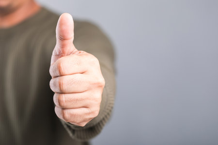 A man giving a thumbs-up with a gray background, leaving space for textâa concept of positivity and encouragementの写真素材