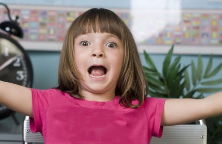 Young child with funny expression on her face while sitting in a class toom