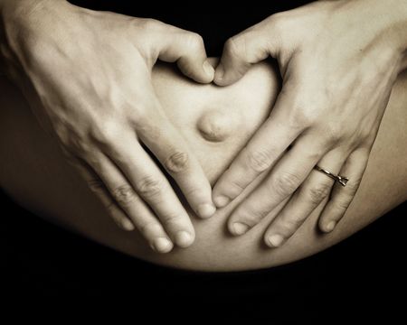 Making a heart shape on pregnant tummyの写真素材