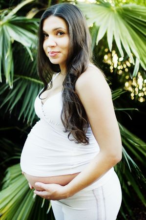 Pregnant woman standing outside in tropical backgroundの写真素材