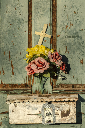 Rustic old weathered and worn doorway with charming display of flowers and crossの写真素材