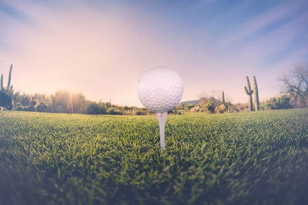 Super wide angle view of golf ball on tee with desert fairway and stunning Arizona sunset in backgroundの写真素材