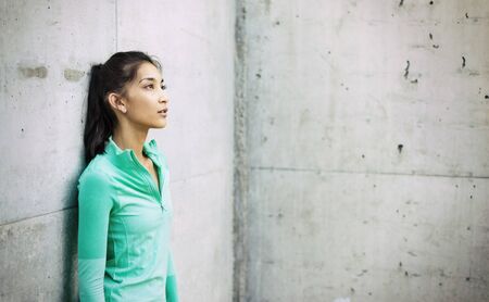 Young active woman leaning against wallの写真素材