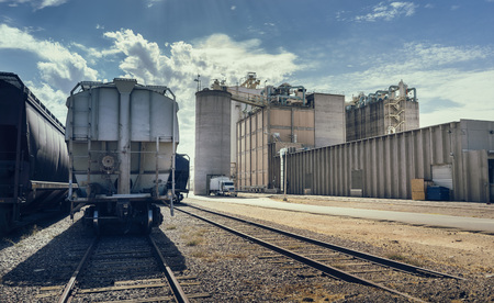 Desert landscape. Arizona heat beats down on industrial building and rail road track with cargo containers, silo and large facility in distance.の写真素材