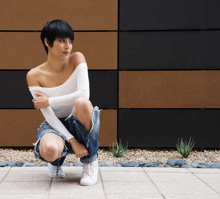 Beautiful young woman wearing ripped denim jeans and off shoulder white topの写真素材