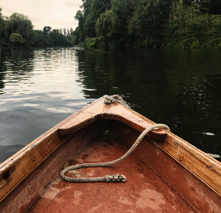 Wood Rowing boat on river, rustic rope, light and shadow painterly water ripples.の写真素材