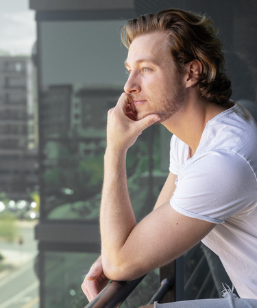 Man thinking looking off balcony of tall buildingの写真素材
