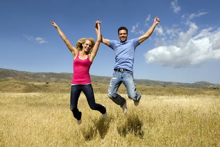 Young couple holding hands and jumpingの写真素材