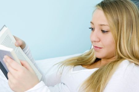Young girl laying on her bed readingの写真素材