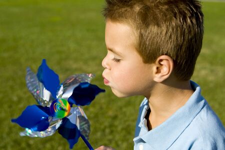 Little boy blowing on a pinwheelの写真素材