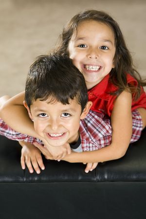 Cute brother and sister sitting on a couchの写真素材