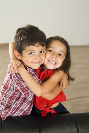 Cute brother and sister sitting on a couchの写真素材