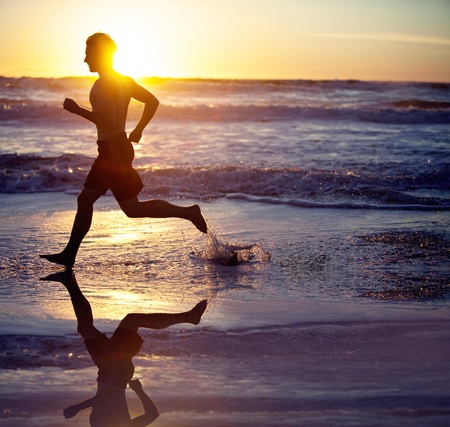 Man running on the beach at sunsetの写真素材