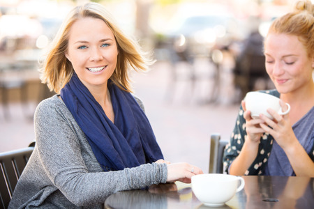 Two girlfriends getting coffee together outsideの写真素材