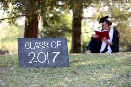 Graduate sitting behind blank chalkboard - room for copyの写真素材