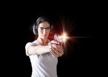 Woman firing a gun with protective gearの写真素材