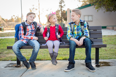 Young school kids sitting on benchの写真素材
