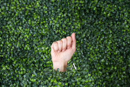 Sign Language Letter A made with hand against green plant backgroundの写真素材
