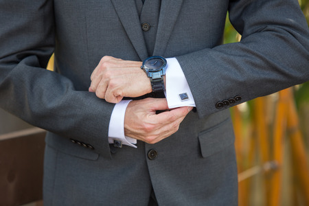 Man adjusting his cufflinks wearing a watch