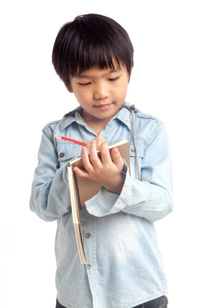 Boy writing on notebook while standing isolated on white backgroundの写真素材