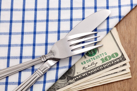 Fork and knife on dollar bills for food business concept