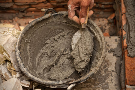 Cement mortar with trowel in worker handの写真素材