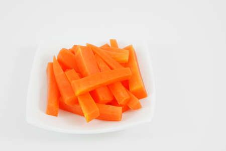 The fresh orange carrot sticks on the white small dish.の写真素材
