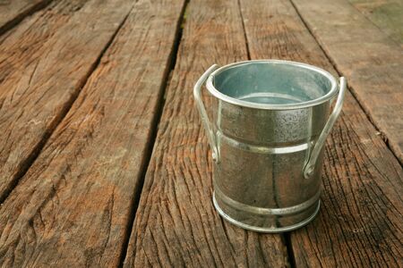The small vintage zinc pot on the old dark brown wooden planks.の写真素材