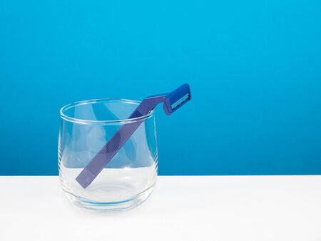 The dark blue plastic razor and round glass for men.の写真素材
