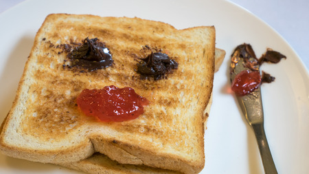 The close up of tasty bread toast and strawberry jam with chocolate spread on white plate.の写真素材