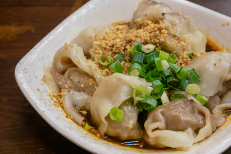 The close up of Taiwanese traditional steamed spicy stinky tofu wontons cuisine on old wooden table at food night market restaurant in Taipei, Taiwan.の写真素材