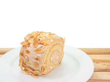 The close up of delicious homemade almond cream roll cake bakery dessert food on wooden plank on white background.の写真素材