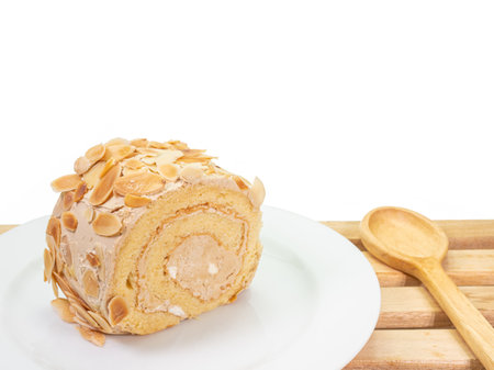 The close up of delicious homemade almond cream roll cake bakery dessert food on wooden plank on white background.の写真素材