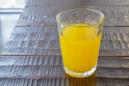 Orange juice drink, a close up of glass of tasty tropical juice beverage on wood table.の写真素材