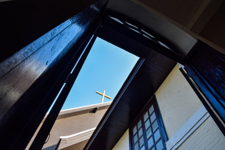 Cross in the window of a Christian church with blue sky background.の写真素材