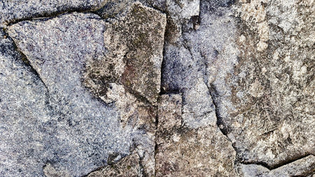 Close-up of a natural mountain rock surface featuring rough and organic textures. Ideal for use in...