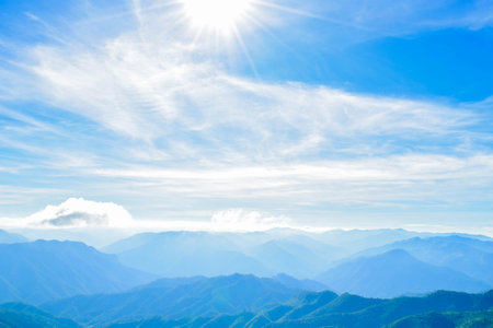 Scenic Mountain Landscape with Blue Sky and Layers of Misty Hillsの写真素材