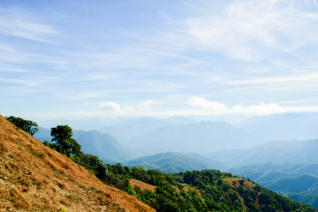 Scenic Mountain Landscape with Blue Sky and Layers of Misty Hillsの写真素材
