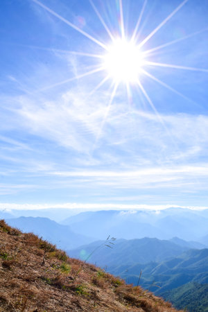 Bright Sun over Mountain Ridge with Layers of Blue Hills and Grassy Slopeの写真素材