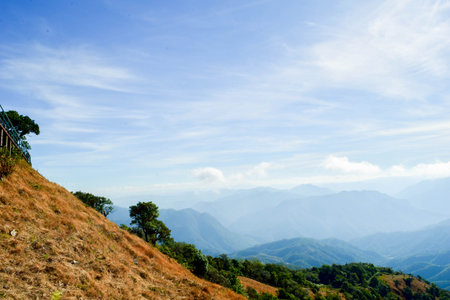 Bright Sun over Mountain Ridge with Layers of Blue Hills and Grassy Slopeの写真素材