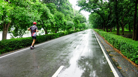 Man Running on Wet Road in Green Park After Rainの写真素材