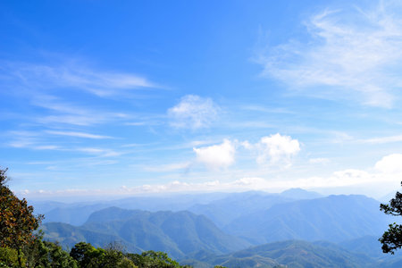 Scenic Mountain Landscape with Blue Sky and Layers of Misty Hillsの写真素材