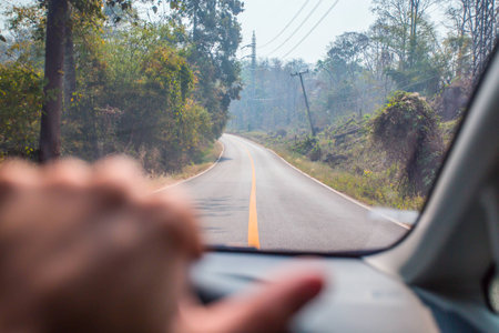 Hands of a driver on steering wheel of a car on the roadの写真素材