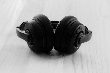 Black and white headphones on a wooden tableの写真素材