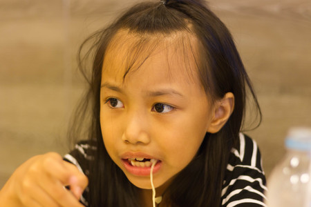 Portrait of bored noodles taste little asian kidの写真素材