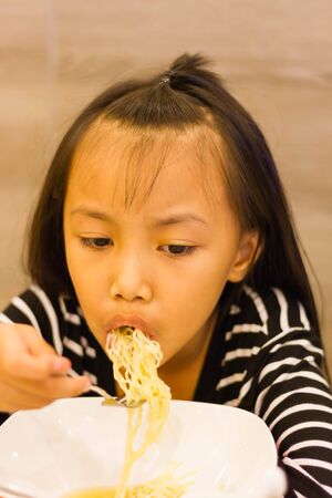 Portrait of bored noodles taste little asian kidの写真素材