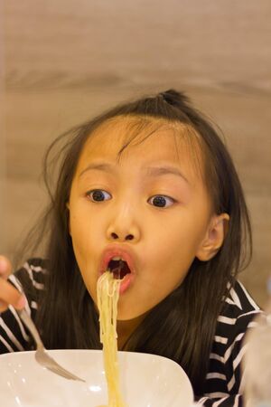 Portrait of Surprised noodles taste little asian kidの写真素材