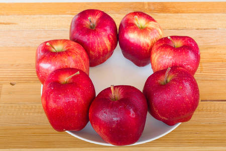 Fresh red apple  on white ceramic plate wood backgroundの写真素材