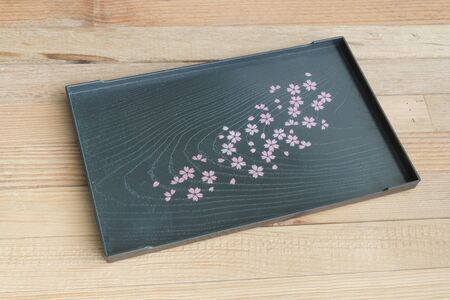 Black tray Sakura's design wooden backgroundの写真素材