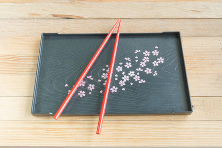 Red chopsticks on black tray Sakura's design wooden backgroundの写真素材